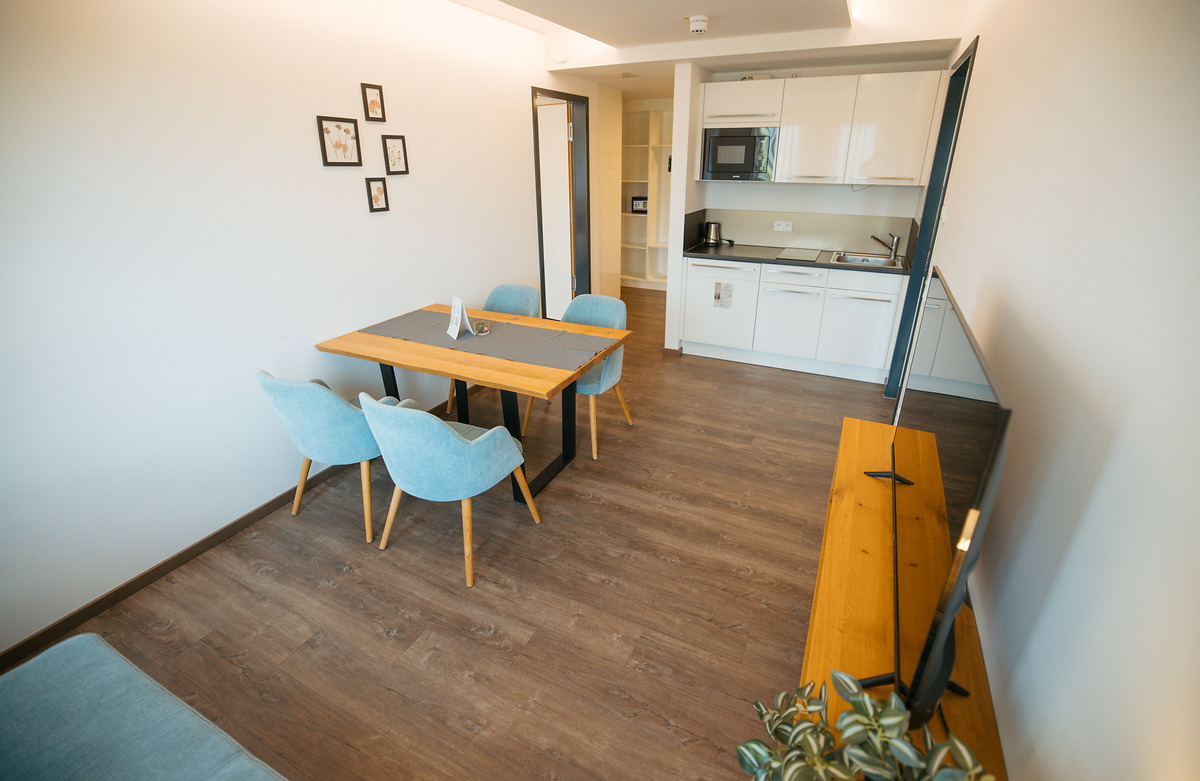 Heller Aufenthaltsraum mit Esstisch und Küchennische im Apartment des Hotel Pöllners