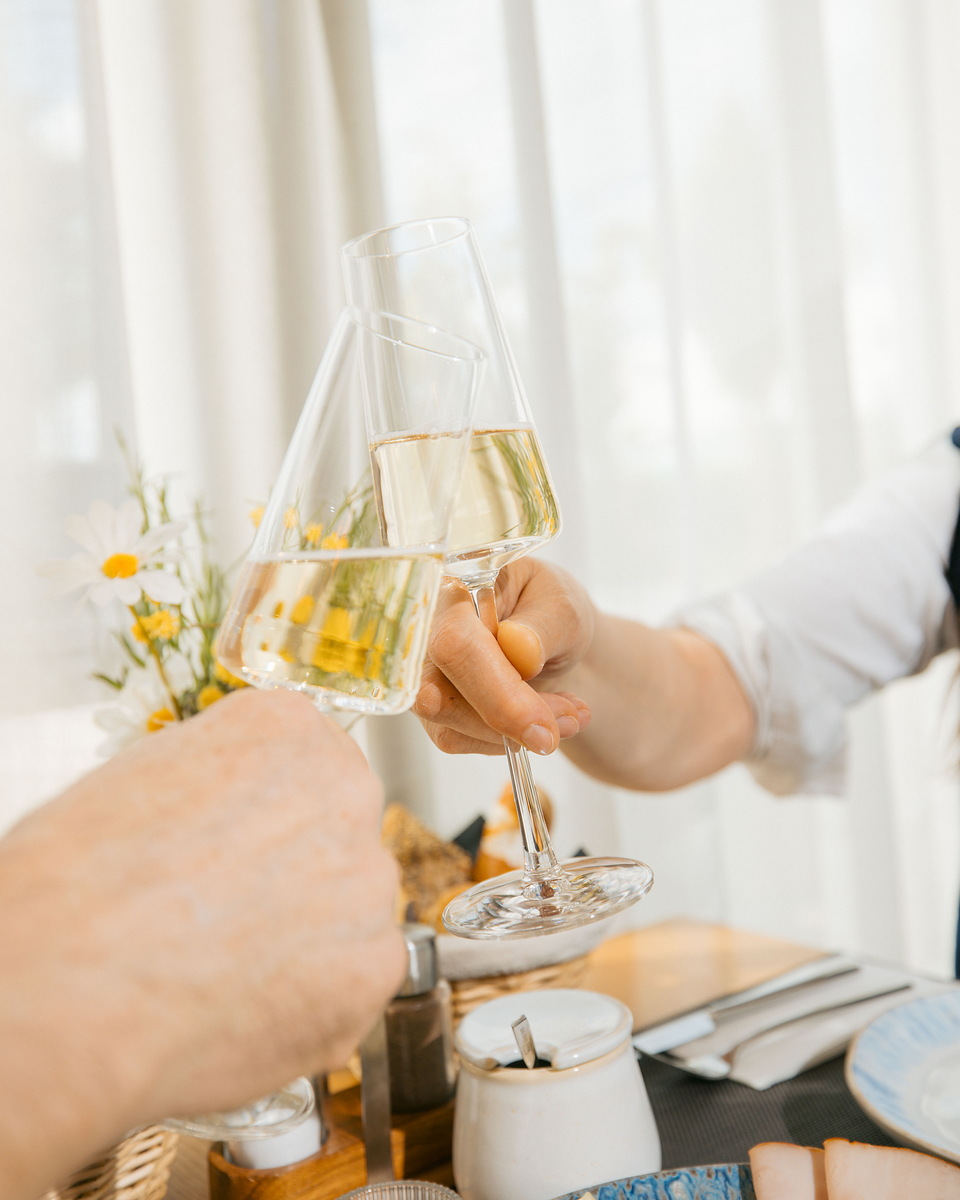 Gäste stoßen beim Essen mit Weißwein an