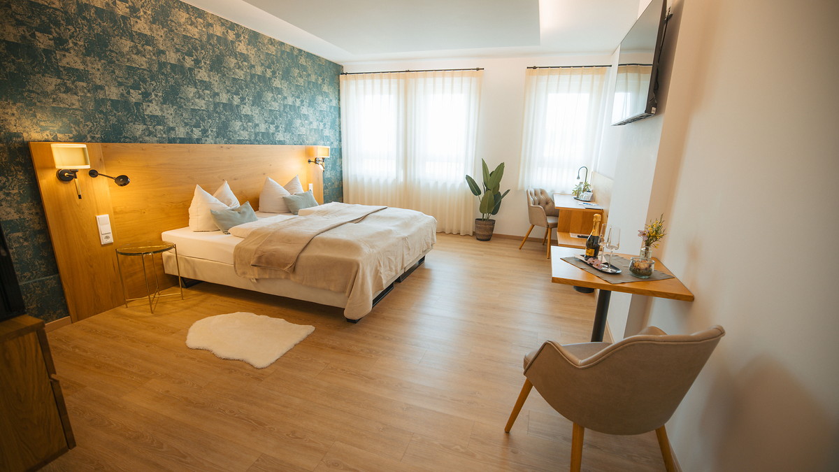 Modernes Hotelzimmer mit Doppelbett, Sessel und Schreibtisch im Hotel Pöllners